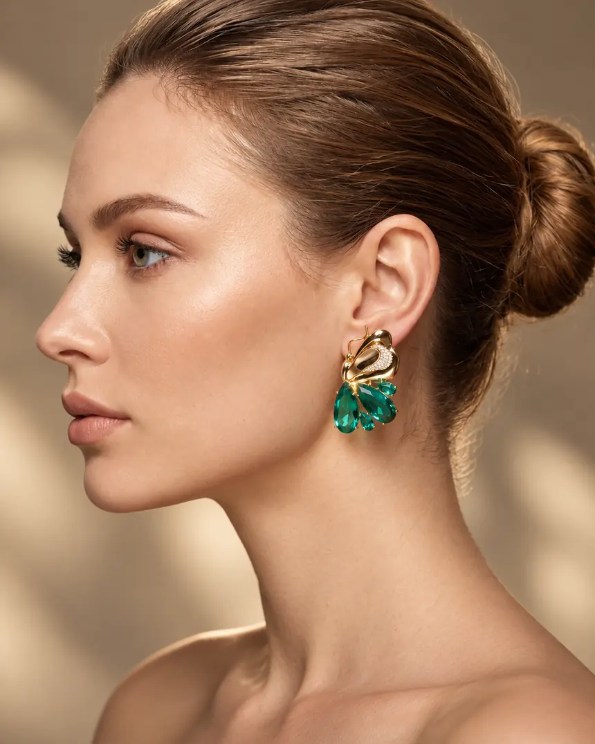 Modelo de perfil usando brinco dourado com gotas cor esmeralda